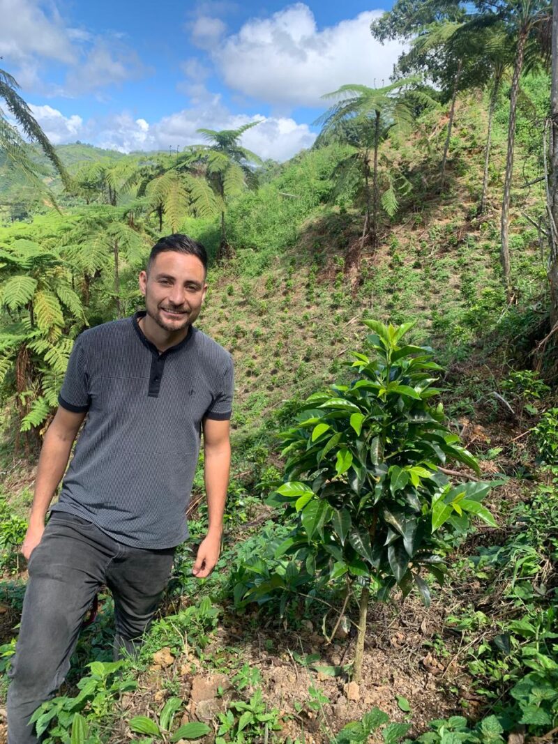Marlon Rojo, Kaffeebauer aus Kolumbien, steht neben einer Kaffeepflanze
